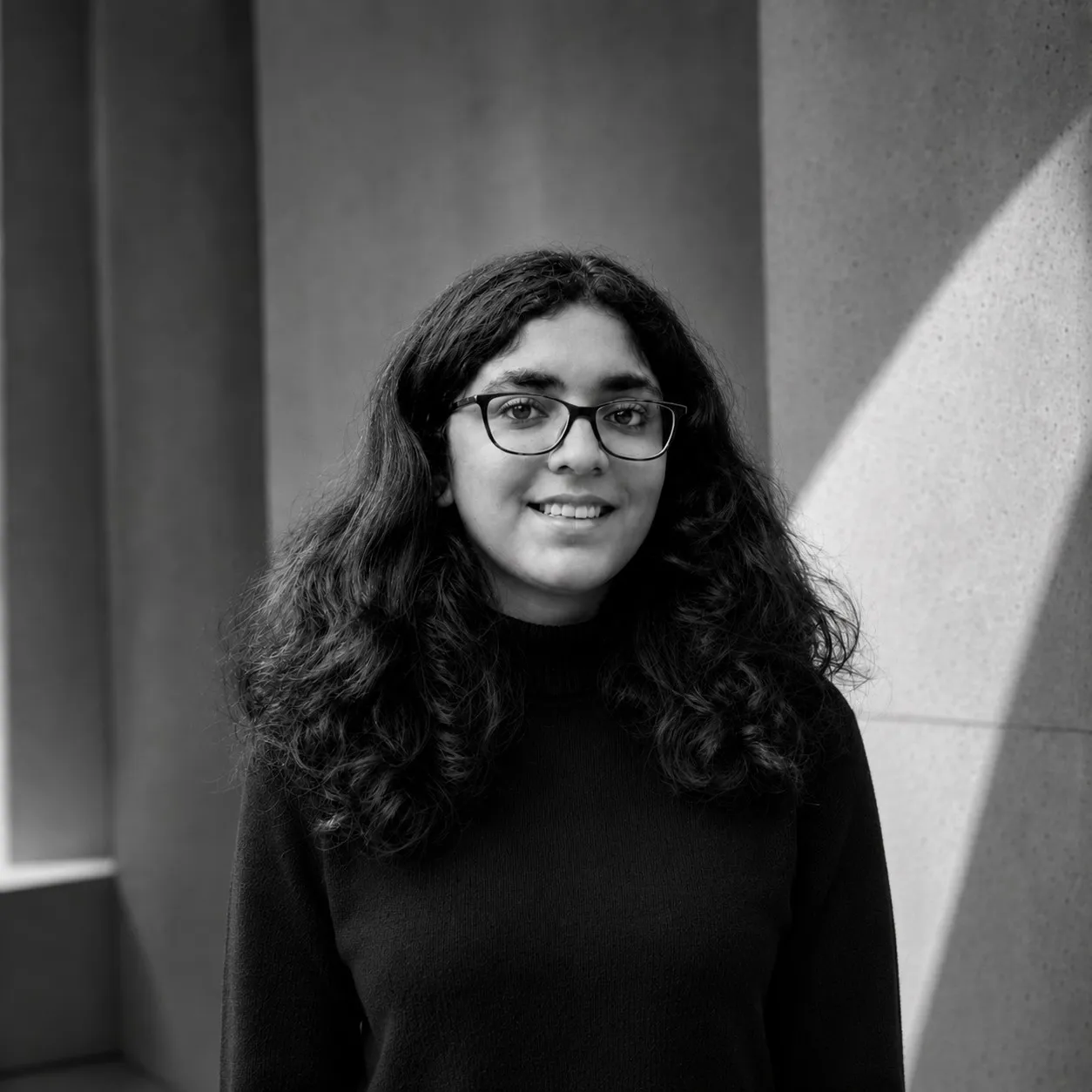 Khushboo Mankani, a black-and-white portrait in front of a concrete wall